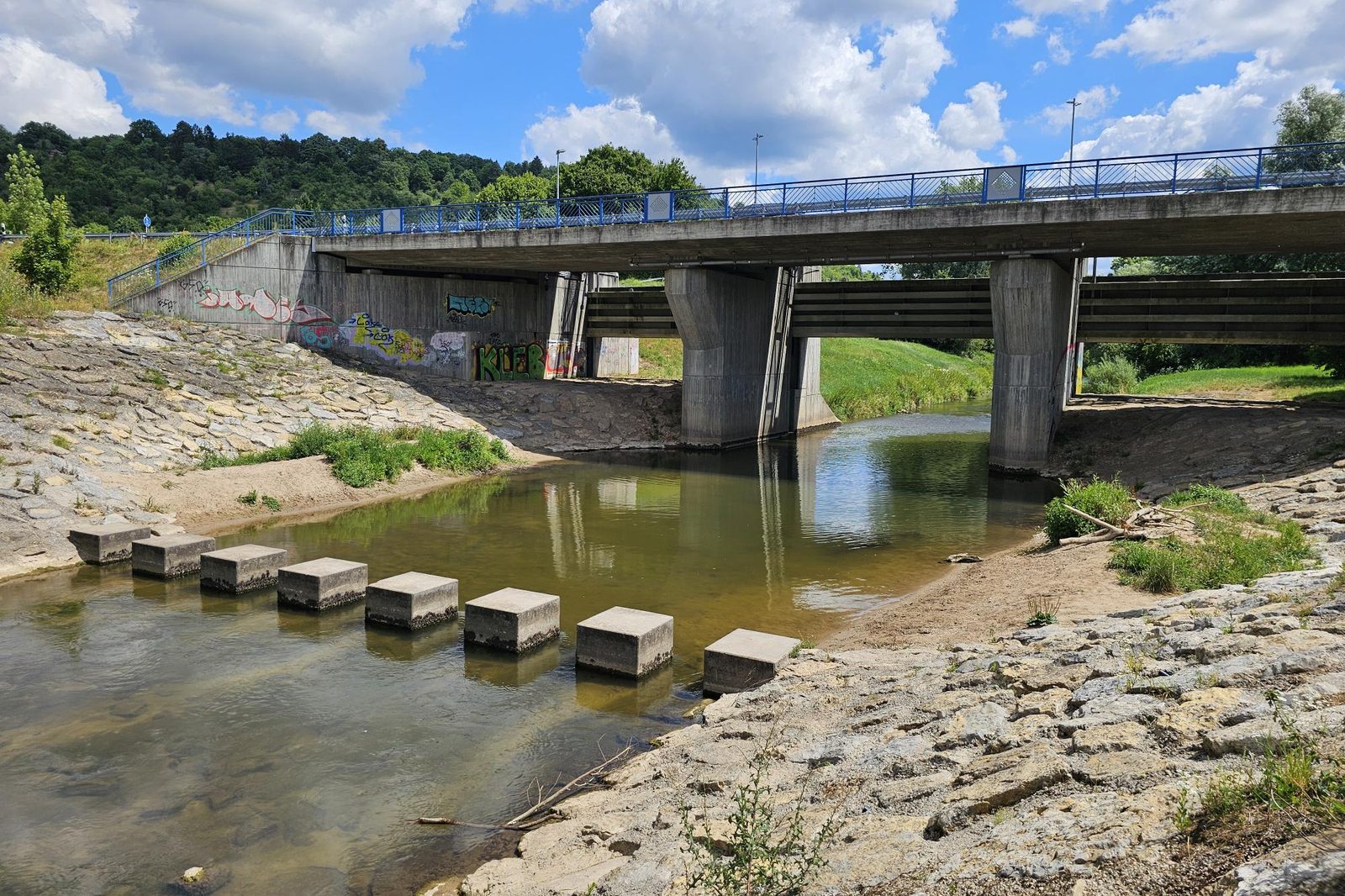 Das Remswehr in Winterbach heute: flaches Wasser unter der Brücke, Trittsteine, befestigte Ufer